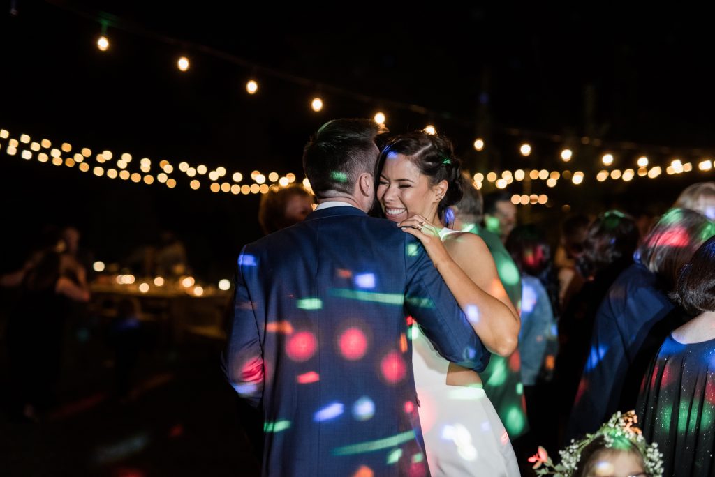bride and groom dancing in colorful dj lights