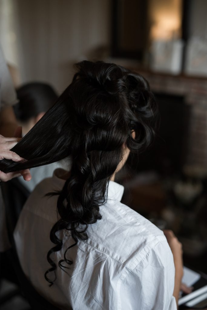 bride getting her hair styled with classic side swept curls